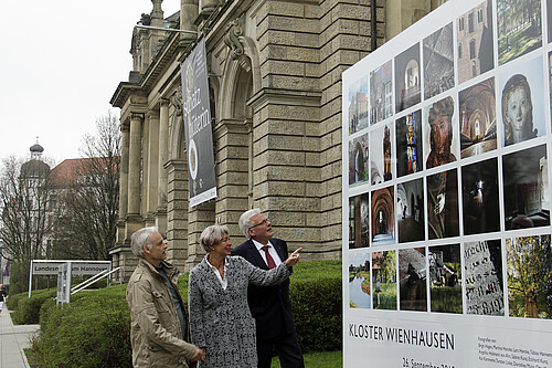 Drei Personen stehen vor einer großen Foto-Installation, im Hintergrund ist die Fassade des Landesmuseums Hannover zu sehen.