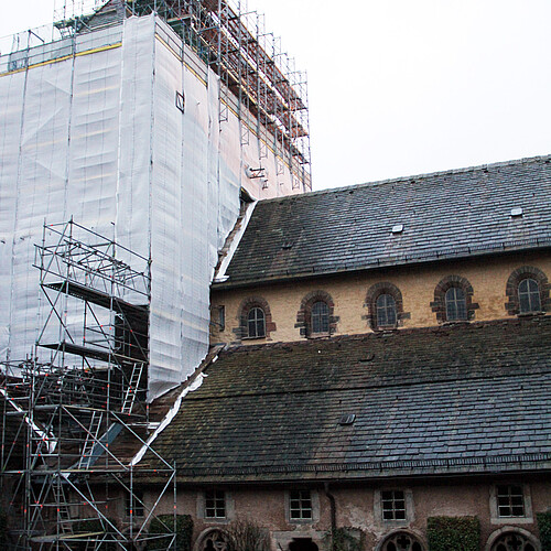 Eine Kirche in der Seitenansicht, der Turm ist von einem Gerüst umgeben.