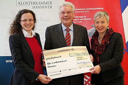 Zwei Frauen und ein Mann, Klosterkammer-Präsident Hans-Christian Biallas, halten gemeinsam einen übergroßen symbolischen Scheck in den Händen.