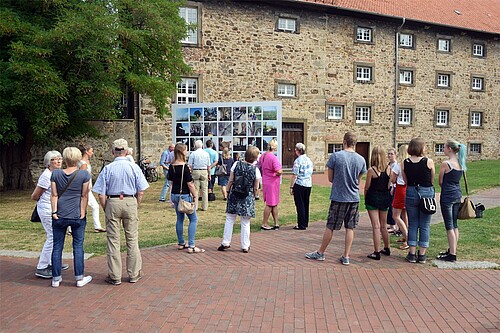 Eine Gruppe von Personen steht vor einer Fotowand.