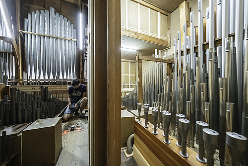 Innenraum einer großen Orgel. Mann hockt auf dem Boden. Vorbereitung einer Kameradrohne.