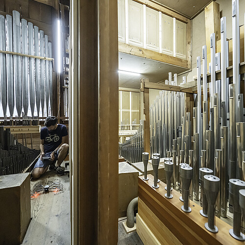 Innenraum einer großen Orgel. Mann hockt auf dem Boden. Vorbereitung einer Kameradrohne.