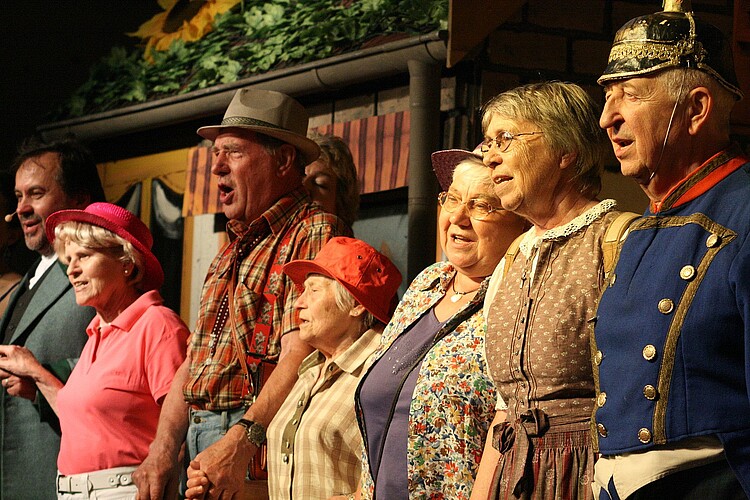 Das Seniorenensemble "La Musica" und "Operamobile" beim Weißen Rössl: Eine Reihe von Senioren sthet verkleidet auf einer Bühne.