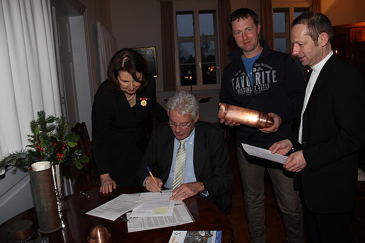 Vier Personen sind um einen Tisch gruppiert. Klosterkammer-Präsident Hans-Christian Biallas sitzt an einem Tisch und unterschreibt ein Dokument.