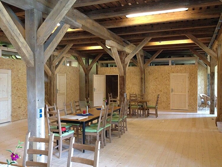 Ein offener Raum in einer Scheine mit einem langen Holztisch und abgehenden Türen.