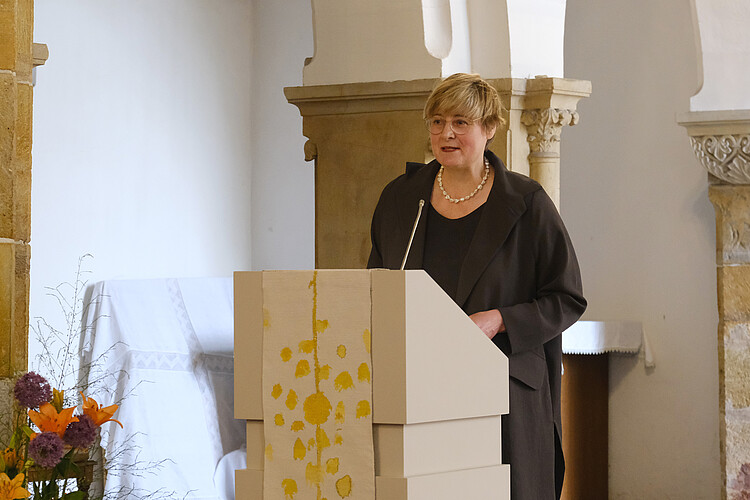 Eine Frau spricht am Rednerpult in einer Kirche.