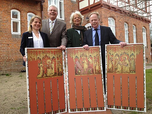 Zwei Frauen und zwei Männer, darunter Hans-Joachim Frey, Leiter der Restaurierungswerkstatt der Klosterkammer Hannover, zeigen Reproduktionen von farbigen mittelalterlichen Fahnen.