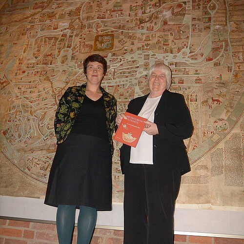 Zwei Frauen stehen vor einer altertümlichen Kartendarstellung.