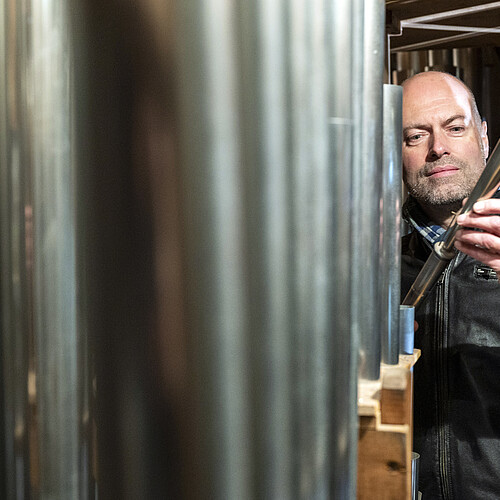 Henning Voss, Kirchenmusiker an der St. Michaeliskirche, steht neben großen Orgelpfeifen.