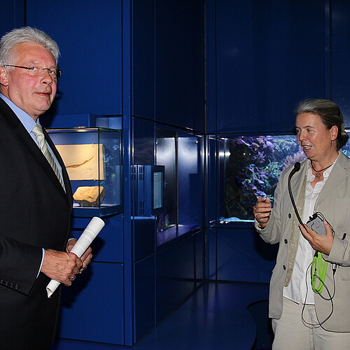 Eine Frau und ein Mann, Klosterkammer-Präsident Hans-Christian Biallas, stehen vor Vitrinen.