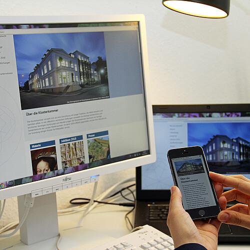 Ein Bildschirm, ein Laptop und ein Smartphone auf einem Schreibtisch - auf allen ist die neue Internetseite der Klosterkammer zu sehen.
