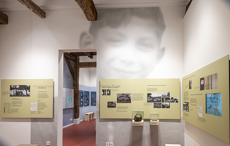 Ausstellungsraum mit Infotafeln und einem großen Schwarz-Weiß-Porträt eines Jungen an der Wand