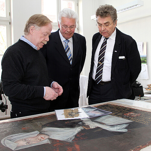 Landtagsvizepräsident Klaus-Peter Bachmann, Klosterkammer-Präsident Hans-Christian Biallas und Hans-Joachim Frey, Leiter der Restaurierungswerkstatt sehen sich ein Äbtissinnen-Portrait aus dem 17. Jahrhundert an.