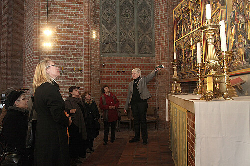 Eine Gruppe von Frauen, darunter Katrin Woitack, Äbtissin des Stifts Fischbeck, steht in einer Kirche vor einem vergolden Bildnis.