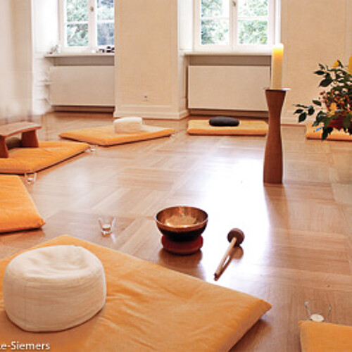 Blick in einen aufgebauten Meditationskreis im Kloster Wennigsen mit Kissen, Blumen und einer Klangschale.