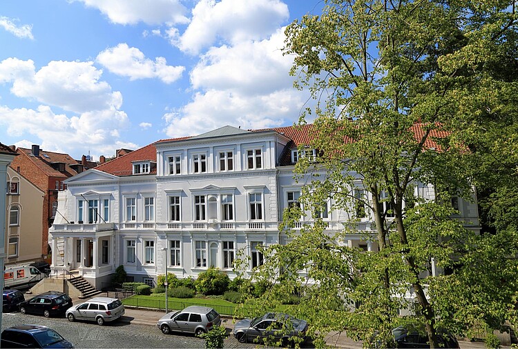 Ein großes weißes Gebäude mit Säulen im Eingangsbereich.