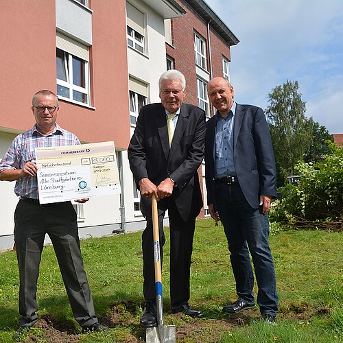 Drei Herren stehen auf einer Wiese nebeneinander. In der Mitte stützt sich Klosterkammer-Präsident Hans-Christian Biallas auf einen Spaten.