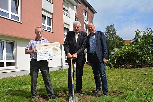 Drei Herren stehen auf einer Wiese nebeneinander. In der Mitte stützt sich Klosterkammer-Präsident Hans-Christian Biallas auf einen Spaten.