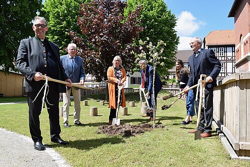 Sechs Personen mit Spaten stehen um einen frisch gepflanzten Apfelbaum herum. Einer von ihnen ist Klosterkammer-Präsident Hans-Christian Biallas.