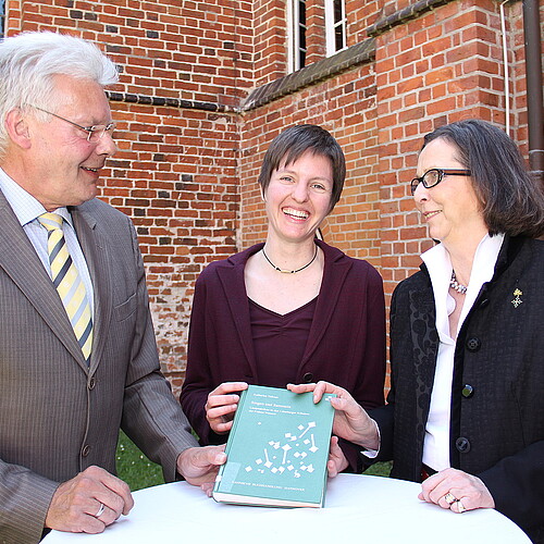 Zwei Frauen, darunter Renate von Randow, Äbtissin des Klosters Wienhausen, und ein Mann stehen gemeinsam an einem runden Tisch und präsentieren ein Buch.