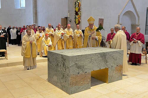 Eine Gruppe von Personen steht vor einem Altar im Hildesheimer Dom.