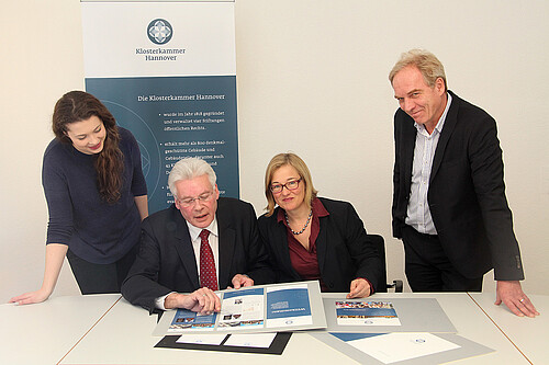 Vier Personen, darunter Klosterkammer-Präsident Hans-Christian Biallas, sind um einen Tisch mit grafisch gestaltete Vorlagen gruppiert.