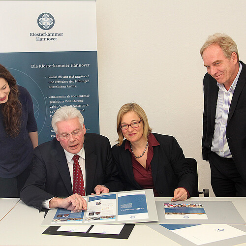 Vier Personen, darunter Klosterkammer-Präsident Hans-Christian Biallas, sind um einen Tisch mit grafisch gestaltete Vorlagen gruppiert.