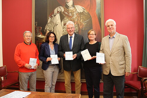 Mitarbeiter der Klosterkammer Hannover, darunter Klosterkammer-Präsident Hans-Christian Biallas, stehen zur Vorstellung der Jubiläumsschrift der Viktoria-Luise-Stiftung vor einem Ölgemälde.