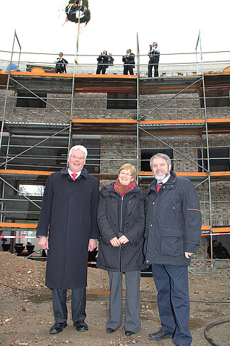 Zwei Männer und eine Frau, darunter Klosterkammer-Präsident Hans-Christian Biallas, stehen vor dem Rohbau des Familienzentrum Plus in Lüneburg.