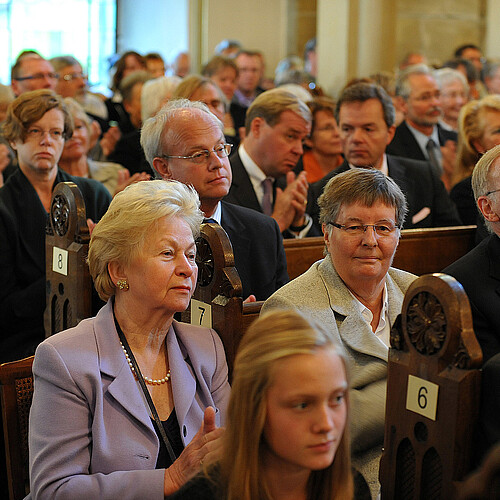 Eine Gruppe von Personen sitzt auf Kirchenbänken.