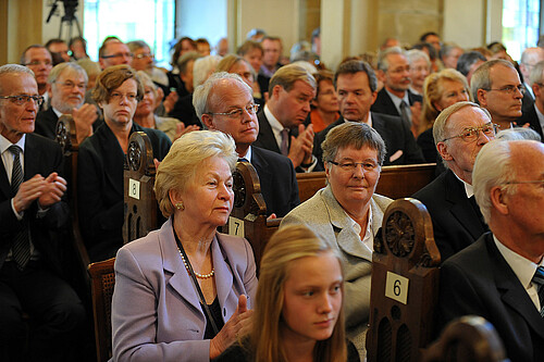 Eine Gruppe von Personen sitzt auf Kirchenbänken.