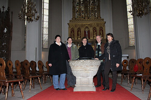 Vier Personen stehen vor dem vergoldeten Hochaltar im Verdener Dom.