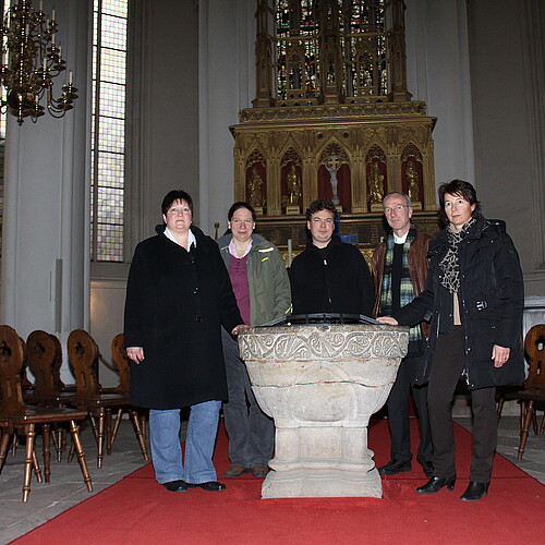 Vier Personen stehen vor dem vergoldeten Hochaltar im Verdener Dom.