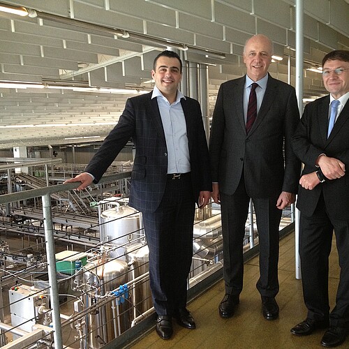Drei Männer, darunter Andreas Hesse, Kammerdirektor der Klosterkammer Hannover, stehen in der Produktionshalle vom Harzer Grauhof Brunnen.