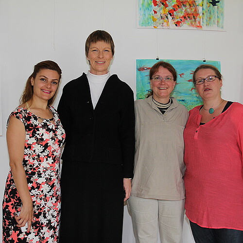 Vier Frauen, darunter Bärbel Görcke, Äbtissin des Klosters Mariensee, stehen vor einer Wand mit selbstgemalten Bildern.