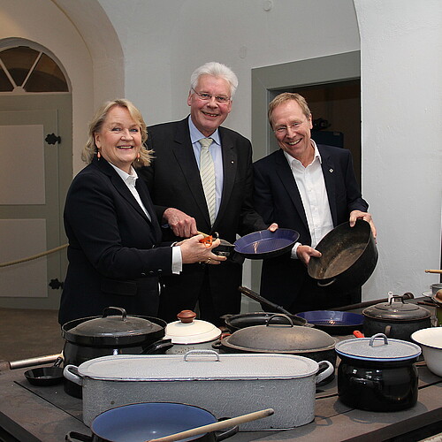 Drei Personen stehen hinter einem historischen Herd.