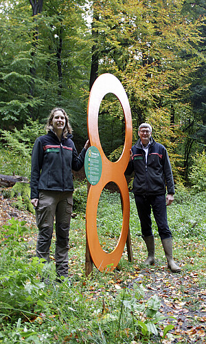 Zwei Personen mit einer Acht im Wald.