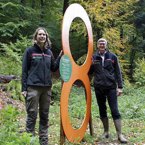 Zwei Personen mit einer Acht im Wald.