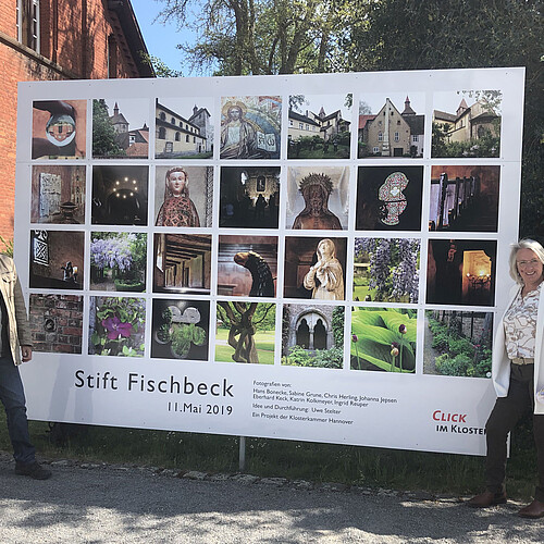 Ein mann und eine Frau stehen an zqwi Seiten einer großformatigen Fotoinstallation mit Bildern aus dem Stift Fischbeck.