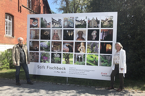 Ein mann und eine Frau stehen an zqwi Seiten einer großformatigen Fotoinstallation mit Bildern aus dem Stift Fischbeck.