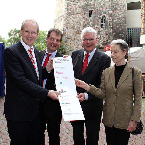 Eine Frau und drei Männer, darunter Klosterkammer-Präsident Hans-Christian Biallas, halten ein Plakat mit den Förderern der Renovierung des hannoverschen Beginenturms in den Händen.