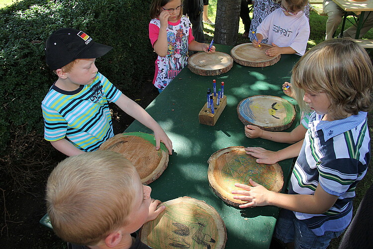 Fünf Kinder bemalen Holzscheiben.