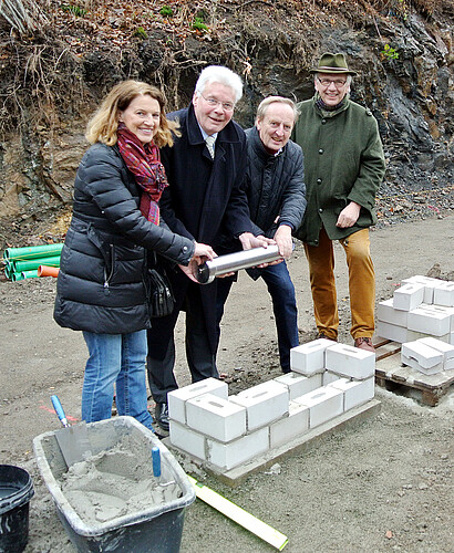 Vier Personen stehen gemeinsam über dem auf das Fundament gelegten Grundstein einer neuen Abfüll- und Lagerhalle der  der Klostergutsbrauerei Wöltingerode GmbH.