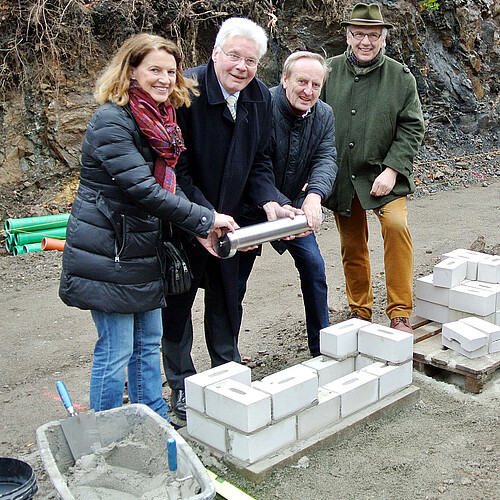 Vier Personen stehen gemeinsam über dem auf das Fundament gelegten Grundstein einer neuen Abfüll- und Lagerhalle der  der Klostergutsbrauerei Wöltingerode GmbH.
