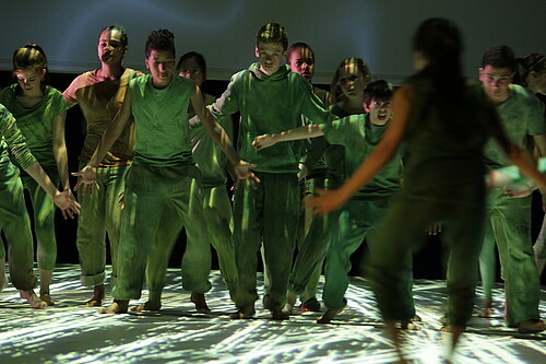 Schülerinnen und Schüler stehen gemeinsam in grünen Kostümen auf einer Bühne.