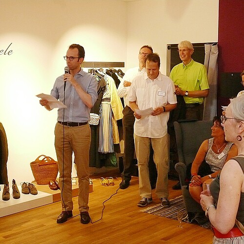 Ein neues Ladengeschäft mit Bekleidung ist zu sehen, mittig steht ein Herr, Bastian Pielczyk aus der Förder-Abteilung der Klosterkammer, und spricht in ein Mikrofon. Rundherum stehen Personen und hören zu.