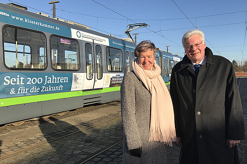 Eine Frau und ein Mann stehen vor einer Straßenbahn.