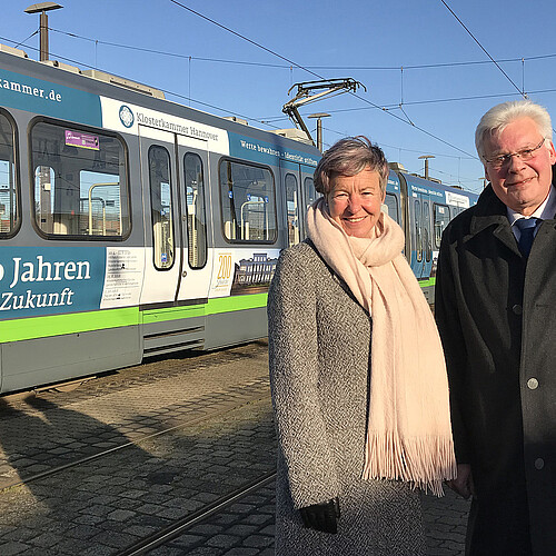 Eine Frau und ein Mann stehen vor einer Straßenbahn.