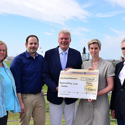 In einer Gruppe von fünf Personen die im Freien stehen halten Klosterkammer-Präsident Hans-Christian und eine Frau einen übergroßen symbolischen Scheck.