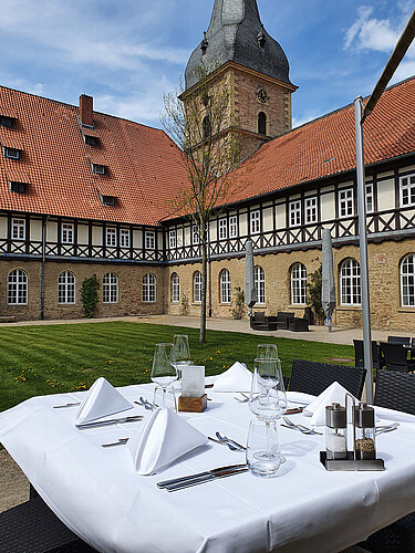 Im Vordergrund ist ein gedeckter Tisch zu sehen im Innenhof des Klosters Wöltingerode, das heute das Klosterhotel beherbergt, zu sehen.